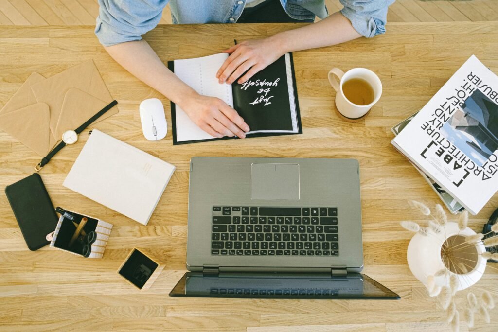 Top-down view of a home office desk with a laptop, coffee, and notes, perfect for freelance work or studying.